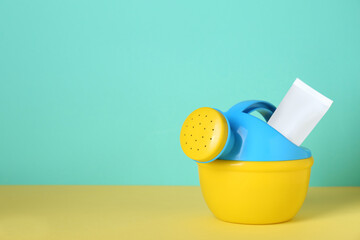 Suntan product and plastic beach toy on color background. Space for text