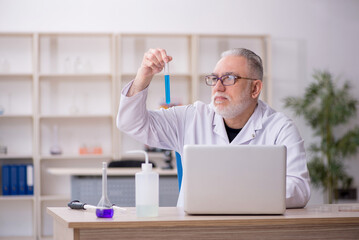 Old male chemist working at the lab