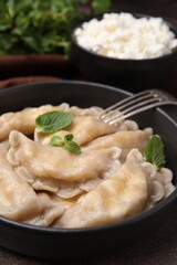 Delicious dumplings (varenyky) with cottage cheese and mint served on table, closeup
