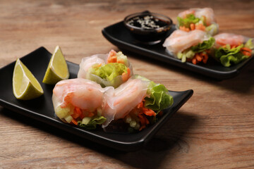 Tasty spring rolls on wooden table, closeup