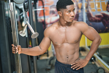 Fototapeta na wymiar An African young male is weight training in a gym, building strength and physical fitness to achieve their desired muscular build.