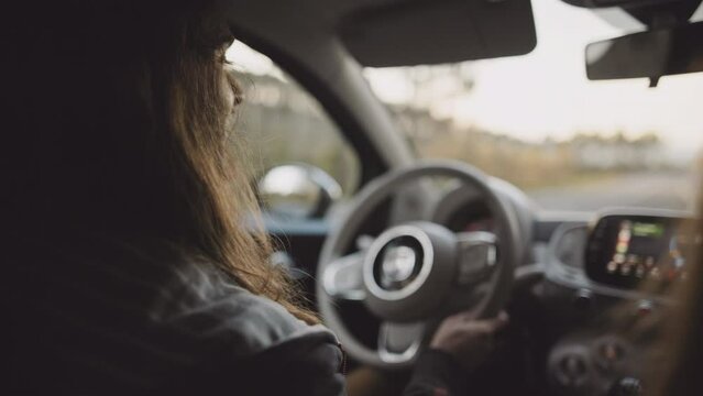 Man driving a car at sunset. Unrecognizable male driver holding steering wheel, sunrise, morning or evening road with lens flare. Young gen z man traveling in a vehicle, road trip. 