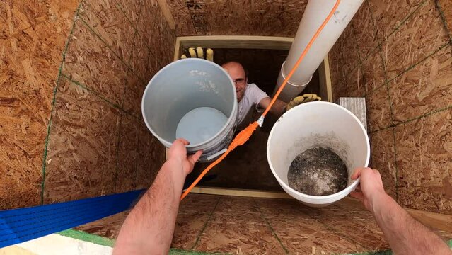 First person view while passing g two buckets to man working on water well deep under ground.