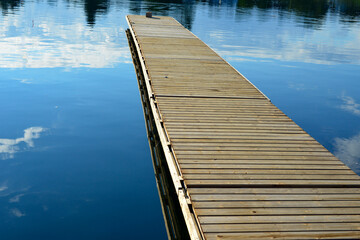 An old wooden boat pier or floating dock with a yellow color mooring deck and a single cleat. The...