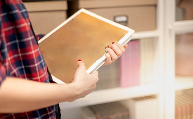 The female hand holding an empty space book in her hand preparing to arrange it in the file folder on the document cupboard at the office.
