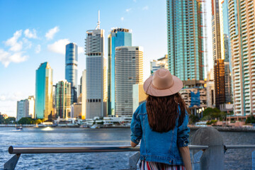 beautiful long hair woman in a hat watching the sunset over brisbane city; city reach boardwalk...