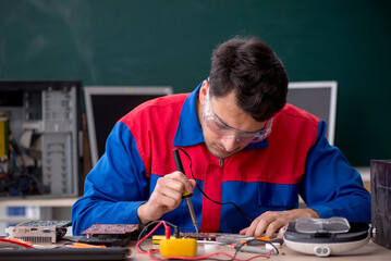 Young male repairman repairing computers in the classroom