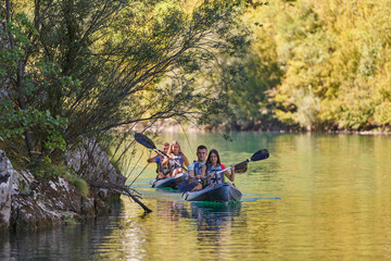 Fototapeta na wymiar A group of friends enjoying having fun and kayaking while exploring the calm river, surrounding forest and large natural river canyons