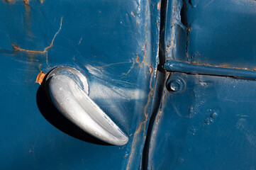 Door handle of an old abandoned blue car. Ready to restore. Old sheet to putty and paint