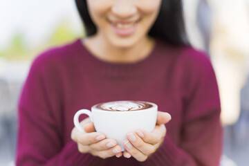 Beautiful Asian young woman holding a coffee cup on a hands close up. Woman enjoy drinking a coffee in morining with breakfast.