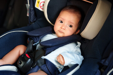happy newborn baby sitting in infant car seat, safety chair travelling
