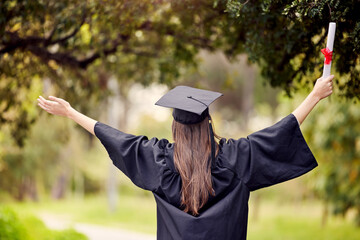 This calls for celebrating. Rearview shot of a young woman cheering on graduation day.
