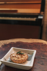 Closeup of small tart almond slice served on wooden table in the cafe.