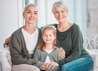 Three generations of females sitting together and looking at the camera. Portrait of an adorable little girl bonding with her mother and grandmother at home. Enjoying a visit with her granddaughter