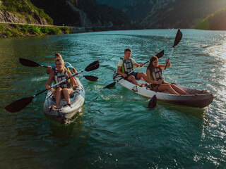 Fototapeta premium A group of friends enjoying fun and kayaking exploring the calm river, surrounding forest and large natural river canyons during an idyllic sunset.