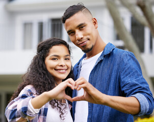 Fototapeta premium Love is here to stay. Shot of a young couple making a heart gesture with their hands in their garden outside.