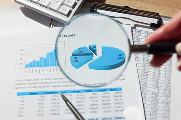 Woman holds magnifier glass above investigational report