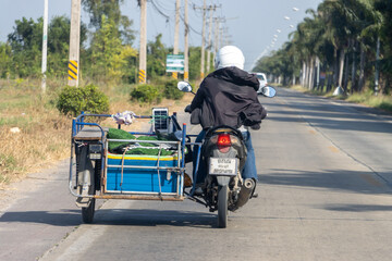 Obraz premium A man carries a load on a sidecar, Thailand