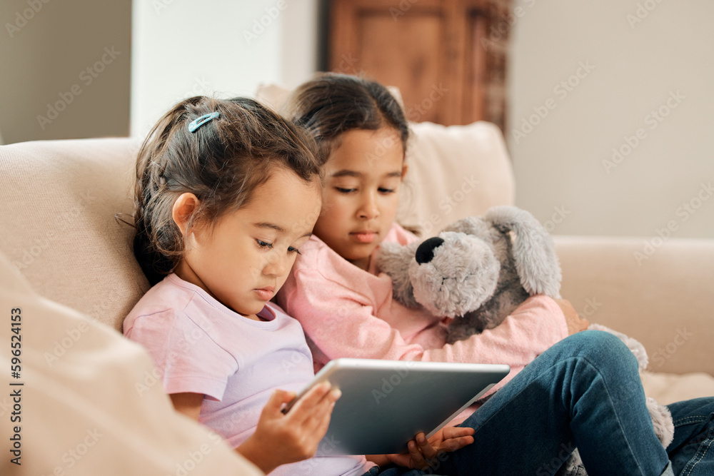 Poster Can we watch something. Shot of two little girls sitting together while using a digital tablet.