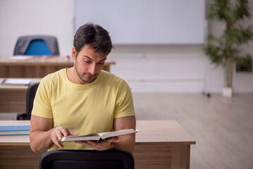 Fototapeta premium Young male student teacher sitting in the classroom