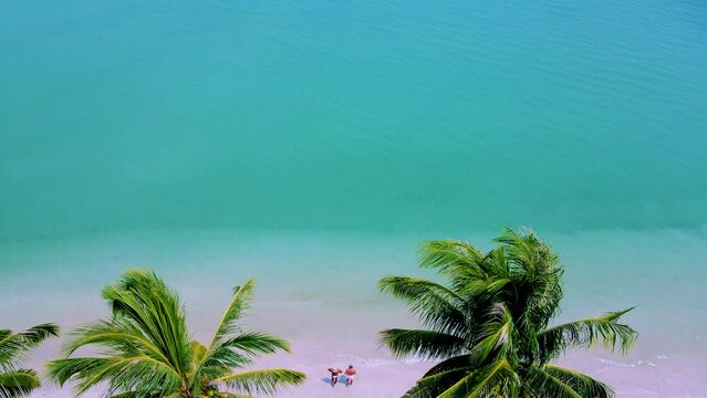 Koh Mook Island or Koh Muk Trat Thailand a tropical white beach with palm trees. A Couple of men and woman on vacation in Thailand walking at the beach
