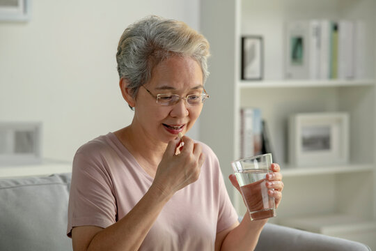 Asian senior woman taking medicine at home, age, medicine, healthcare and people concept