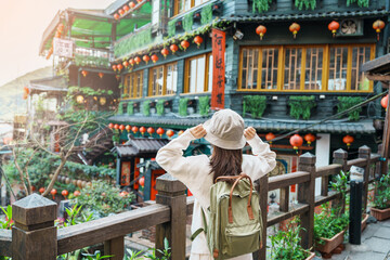 woman traveler visiting in Taiwan, Tourist with hat and backpack sightseeing in Jiufen Old Street village with Tea House background. landmark and popular attractions near Taipei city. Travel concept - obrazy, fototapety, plakaty
