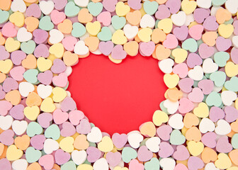 Brightly colored candy hearts, white card with red heart empty space in center for copy space. Valentine's Day.