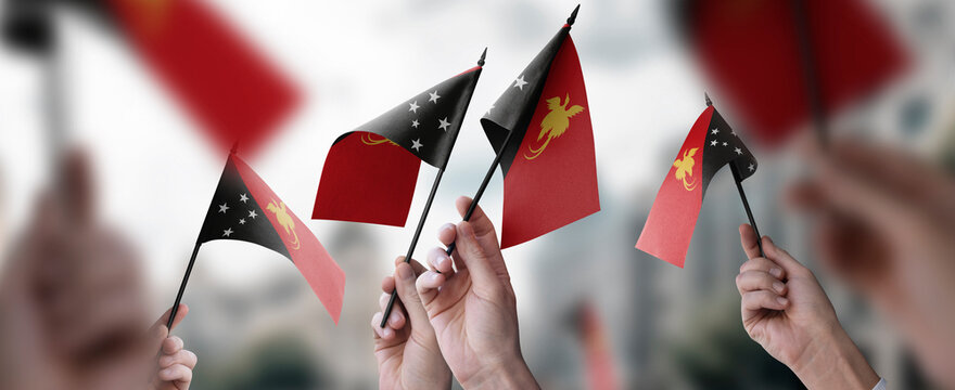 A group of people holding small flags of the Papua New Guinea in their hands