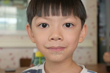 little messy boy with dirty mouth, funny happy kid portrait, tasty food