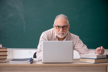 Old male teacher sitting in the classroom