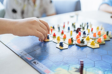 Board game playing concept. People hands hold meeple figures for playing board game on board game field with many figure, dice, models at home. Playing game with friends, family, child on holiday trip