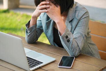 woman sitting down, his face unsettled. At the computer desk she has headaches and stress. Cause of...