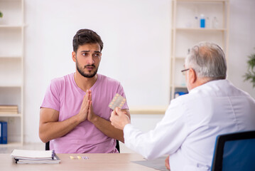 Fototapeta premium Young male patient visiting old male doctor