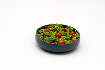 Green vegan salad from green leaves mix and vegetables on white background.