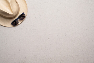 Summer, beach and vacation concept with free text space. Top view. Flat layout with a man straw hat and sun glasses in the upper left corner on a fine sandy background