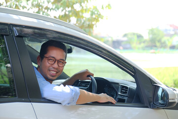 Asian man looking from inside his car with happy expression