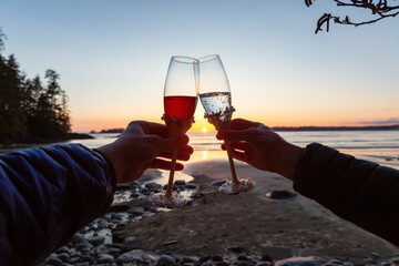 Man and Woman Cheers with Champagne Flute Glasses on the Beach at Sunset. Tofino, Vancouver Island, British Columbia, Canada.