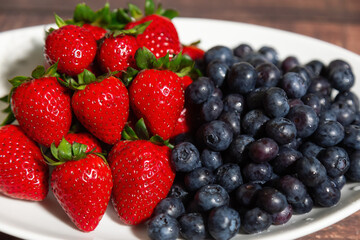 Fresh Bowl of strawberries and blueberries on a wooden table.