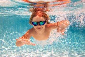 Kid swimming in pool underwater. Child boy swim underwater in sea. Child playing and diving in swimming pool. Funny kids boy play and swim in sea or pool water. Summer vacation concept.