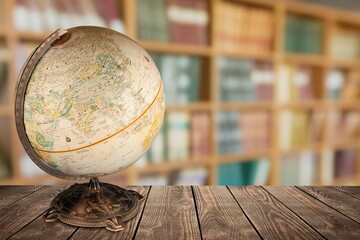 An old retro globe on the table on bookcases background