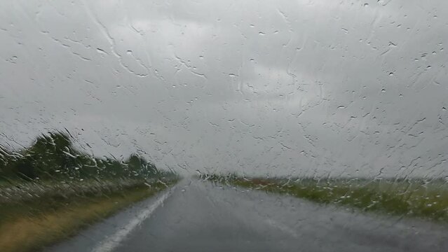 Raindrops on the windshield of the car rise up from the oncoming wind. Road trip in the rain