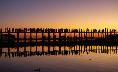 Fototapeta premium Amarapura, Myanmar - November 22, 2016: Unidentified people walk on U Bein bridge at sunset in Myanmar. U Bein bridge is the longest teak bridge in the world.