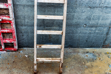 Wooden ladder at the construction site against the background of a concrete wall. Work at height. Security engineering.