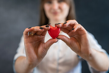 Female nurse in uniform with the stethoscope holding small red heart