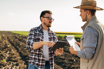 Farm owner and a worker are standing in the fields and talking