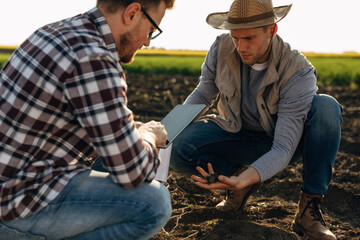 A farmer and a scientist are working together in the field to check the fertility of the soil