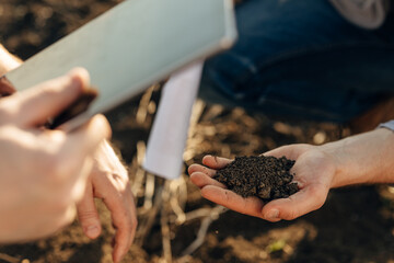 Closeup view of male hands holding soil for fertility examination.