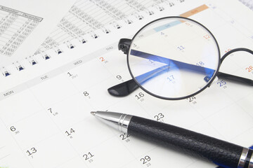 Naklejka na ściany i meble Round eyeglasses and pen on calendar close up. Planning business concept.