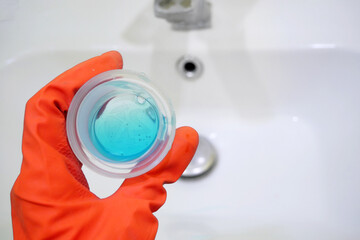 woman cleaning a bathroom's sink cleaner, Person cleaning the kitchen sink with a glove, closeup..